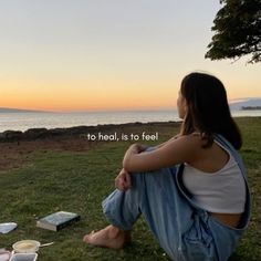 a woman sitting on the ground with food and water in front of her, saying to heal, is to feel