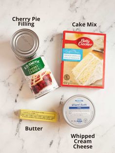 ingredients to make cake mix laid out on a marble counter top, including butter, whipped cream and cherry pie filling