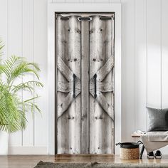 an open wooden door with metal handles in a white living room next to a potted plant