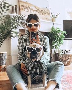 a woman sitting on the floor with her dog wearing sunglasses and holding a camera in front of her face