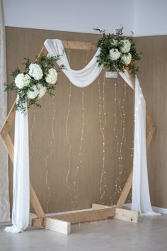 a wedding arch decorated with white flowers and greenery