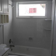 a bathroom with a toilet, sink and bathtub next to a window in the wall