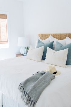 an instagram photo of a bed with white linens and blue throw pillows on it