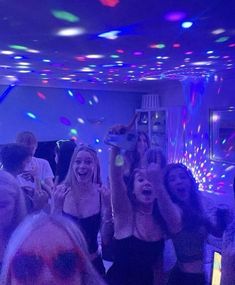 a group of people standing around each other in a room with lights on the ceiling