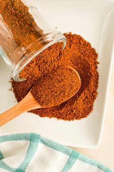 a wooden spoon with spices in it on a white plate