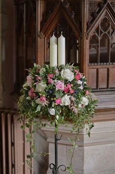 a candle holder with flowers and greenery on it