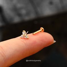 a person's finger with a tiny gold nose ring on it and a small diamond in the middle