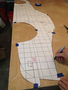 a person is cutting out a pattern on a piece of wood with scissors and tape