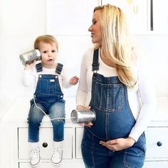 a woman is holding a baby while sitting on a dresser with two cups in her hands