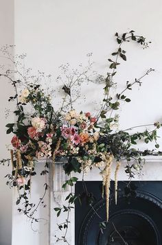 flowers are arranged in vases next to a fireplace