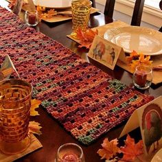 a crocheted table runner is set on a dining room table with fall leaves