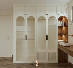 an empty room with white cabinets and wood shelves on the wall, in front of a mirror