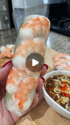 a person holding up some food next to a bowl of soup