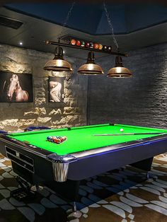 a green pool table sitting in front of two lamps