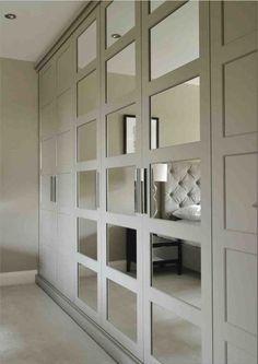 an empty room with mirrored doors and white furniture