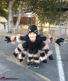 a child in a costume that looks like a spider is standing on one leg and smiling