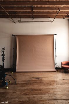 an empty photo studio with soft lighting and wooden flooring, including a large pink backdrop