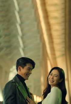 a man and woman standing next to each other in front of a ceiling with lights