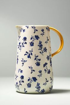 a blue and white flowered vase with gold handles on a gray background, sitting in front of a grey wall