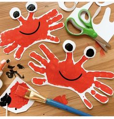 handprints and scissors on a wooden table with paper cut out to look like frogs