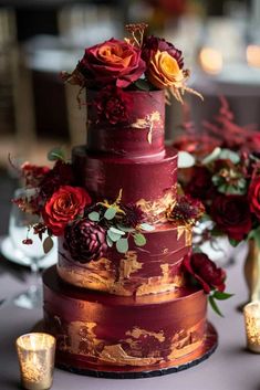 a red and gold wedding cake with flowers on top