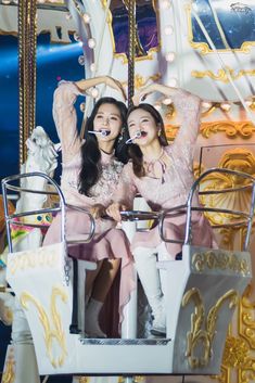 two girls are riding on a merry go round