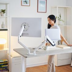 a woman standing in front of a desk with a computer on it