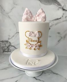 a white cake decorated with pink and gold bows on top of a marble countertop