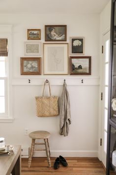 a white room with pictures on the wall and a wooden stool in front of it