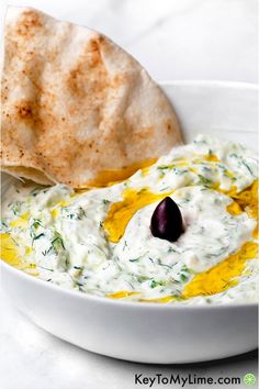 a white bowl filled with dip next to a tortilla