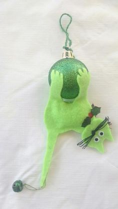 an ornament shaped like a green creature laying on top of a white sheet