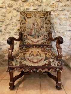 an old chair with ornate carvings on it in front of a stone wall and floor