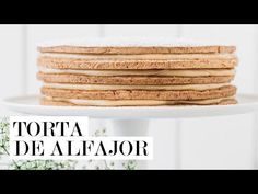 a stack of cookies sitting on top of a white cake stand with the words alfajor cake above it