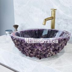 a bathroom sink with purple marble and gold faucet