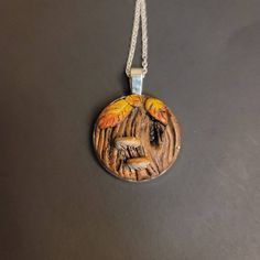 a wooden pendant with an image of a bird on it's back and two birds perched on the tree branches