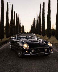 an old black sports car driving down the road