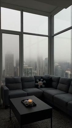 a living room with large windows and a gray couch in front of a coffee table