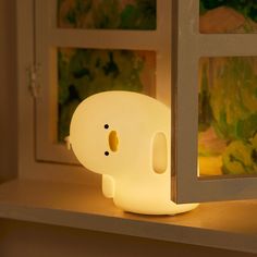 an elephant shaped light sitting on top of a shelf in front of a window sill