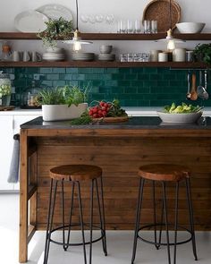 two stools sit at the center of a kitchen island in front of an open shelving