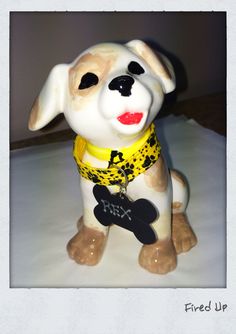 a dog figurine with a yellow bandana on it's collar and name tag