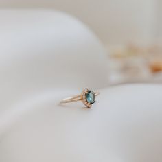 an engagement ring with a blue topaz sits on a white surface