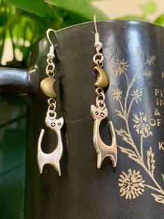 Inspired by mid century atomic cats, these charming little silver and bronze mixed metal tone cat earrings are a great match for any outfit! ✨Great for vintage and cat lovers alike! Measure approximately 1.5" long.  Hooks are sterling silver, nickel free and hypoallergenic. Made to order! Gold Metal Cat Design Earrings, Gold Metal Earrings With Cat Design, Cat Design Metal Drop Earrings, Metal Cat Design Drop Earrings, Vintage Silver Cat Design Jewelry, Atomic Cat, Cat Charm, Cat Earrings, Wire Work