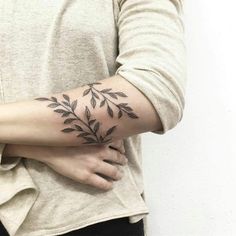 a woman's arm with a tattoo on it that has leaves growing out of it