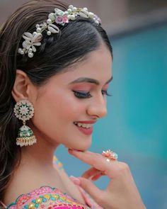 a woman with long hair wearing a tiara and earrings