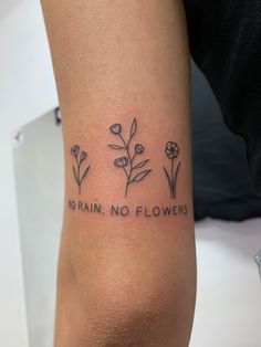 a woman's arm with three flowers and the words no rain, no flowers on it