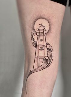 a woman's leg with a lighthouse tattoo on the side and waves coming out of it