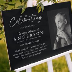 a black and white sign with an image of george michael anderson on it, surrounded by greenery