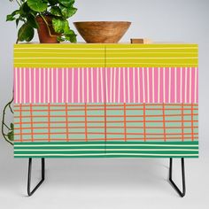 a potted plant sitting on top of a wooden cabinet next to a green plant