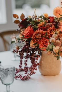 a vase filled with flowers sitting on top of a white tablecloth covered dining room table