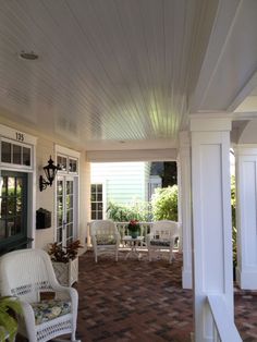 a porch with white furniture and brick flooring